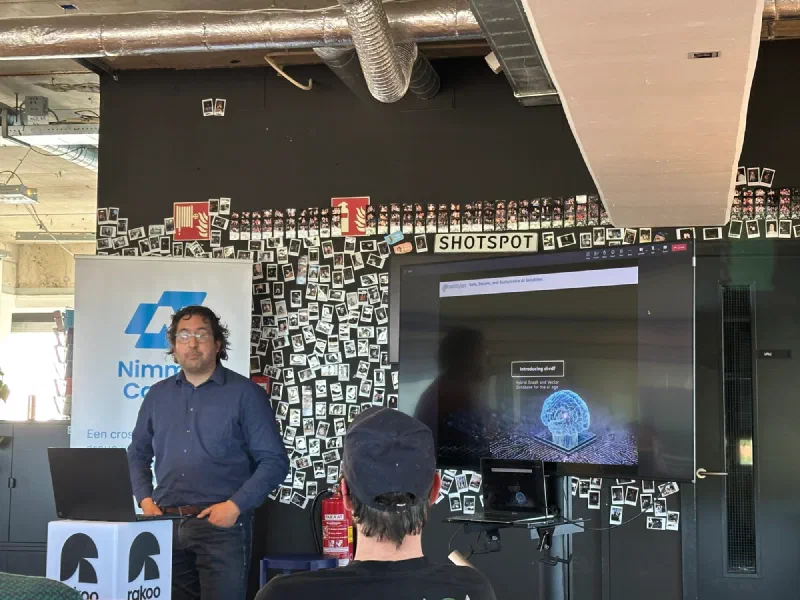 Een spreker staat naast een Nimma Codes-banner en een scherm over een graph- en vectordatabase